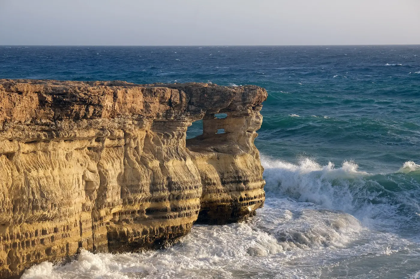 Golden sea cliffs and waves at Cape Greco, Cyprus